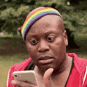 a man wearing a rainbow headband is looking at a cell phone .