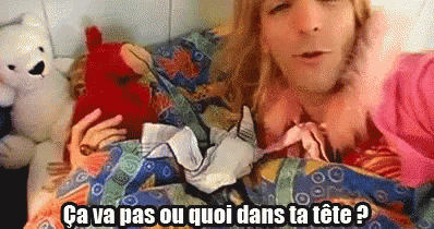 a man is laying in bed with a bunch of clothes and a teddy bear and says ca va pas ou quoi dans ta tete