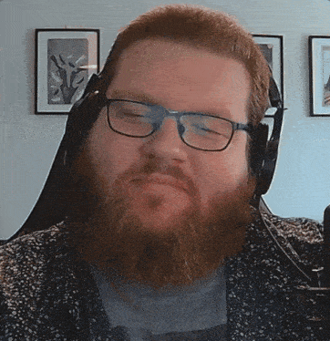 a man with glasses and a beard looks at the camera