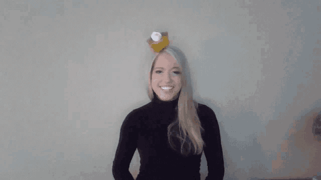 a woman wearing a black turtleneck and a cupcake on her head