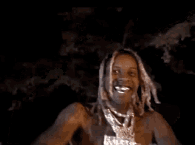 a man is standing in the dark with his arms outstretched and smiling at the camera .