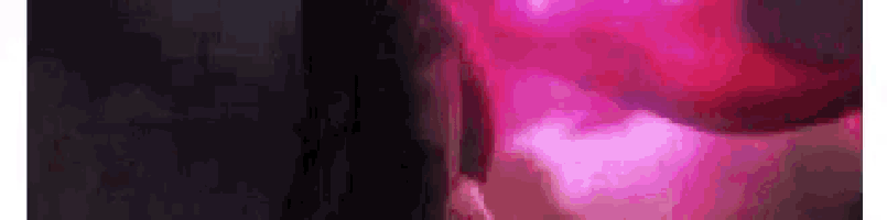 a close up of a pink light shining on a dark background .