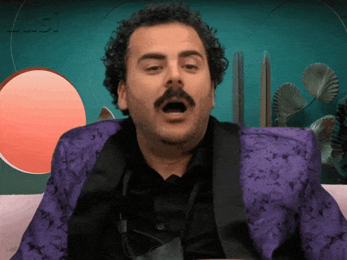a man in a purple suit and black shirt is sitting on a couch with his mouth open