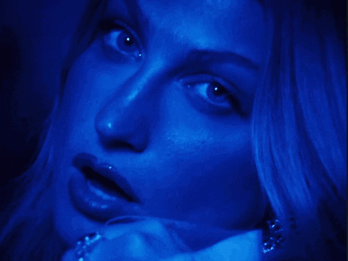 a close up of a woman 's face with blue lights behind her