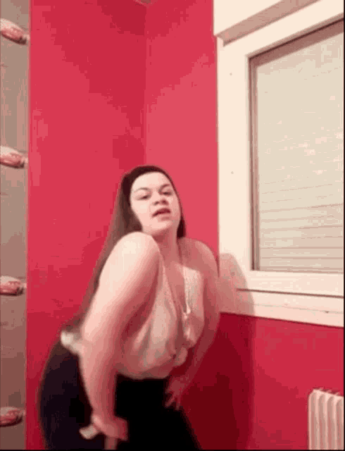 a woman is dancing in front of a window in a room with cars on the wall .