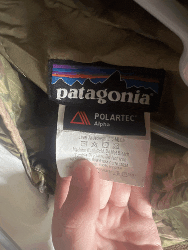 someone is holding a patagonia polartec alpha label