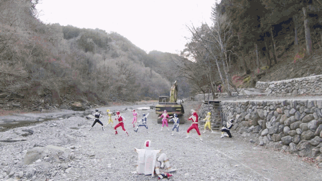 a group of power rangers are standing on a rocky beach