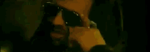 a man wearing sunglasses and a watch is talking on a cell phone .
