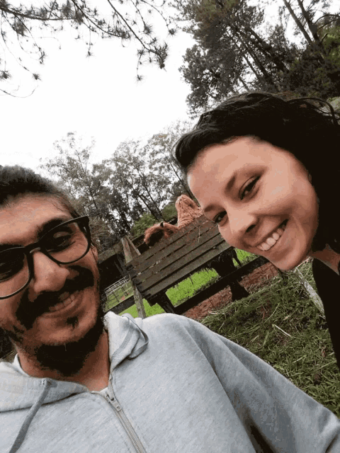 a man and a woman are posing for a picture in front of a wooden fence