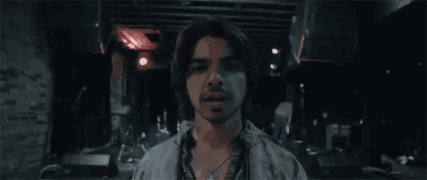 a man is standing in a dark room with his arms outstretched and a sword in his hand .