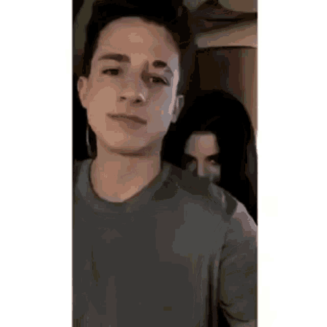 a man and a woman are standing next to each other . the man is wearing a grey shirt .