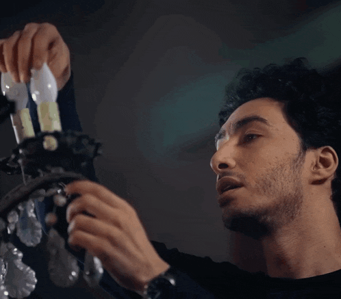 a man is fixing a chandelier with a light bulb