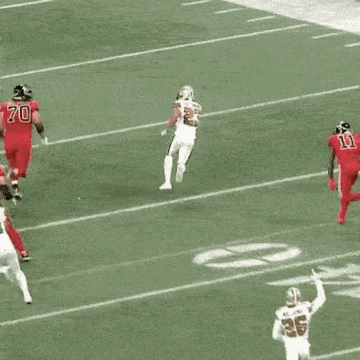 a group of football players are running on a field . one of the players has the number 11 on his jersey .