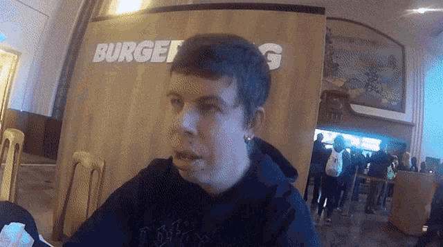 a man sitting in front of a sign that says burger g