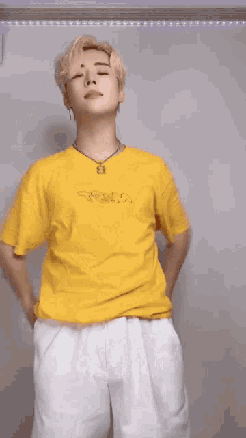 a man wearing a yellow shirt and white pants is dancing