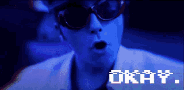 a man wearing sunglasses says " okay " in a pixelated image