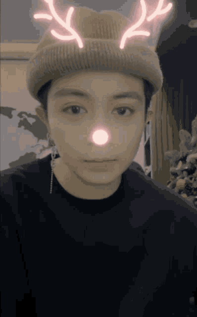 a person wearing a hat with antlers on it and a pink nose