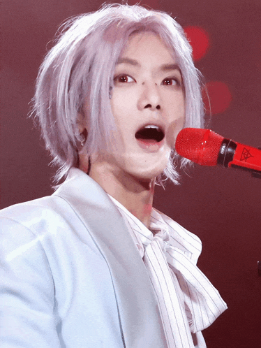 a close up of a person singing into a microphone with a triangle on it