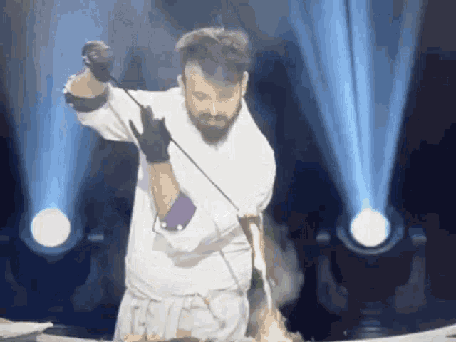 a man with a beard is cutting a cake with a sword on a stage