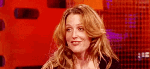 a woman with long blonde hair is sitting in front of a red background .