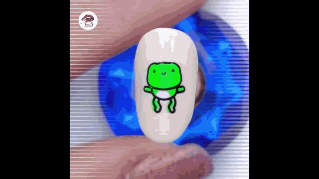 a close up of a person 's nails with a green frog on it