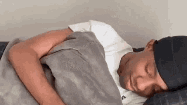 a man is sleeping on a bed with his head on a pillow and a blanket .