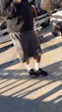 a man wearing shorts and socks is standing on a sidewalk .