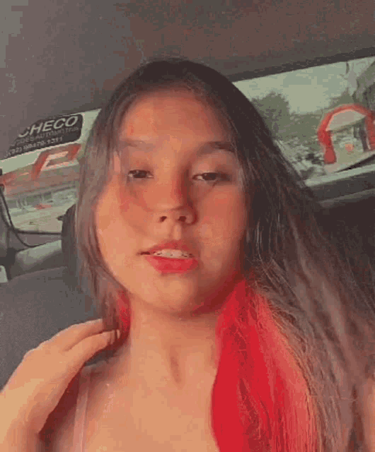 a girl with red hair is sitting in a car and looking at the camera .