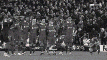 a group of soccer players standing in front of a crowd and a sign that says simply