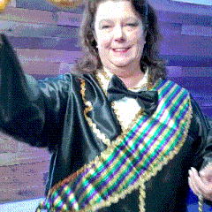 a woman wearing a black jacket with a purple and green sash around her waist