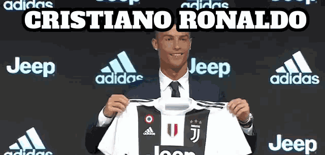 a man in a suit and tie holds up a jeep jersey