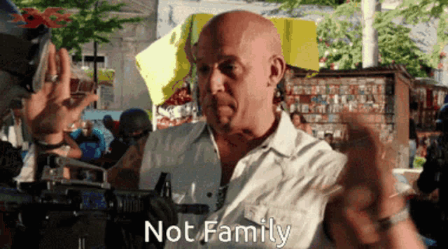 a bald man in a white shirt holds a gun and says not family