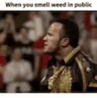 a man in a military uniform is standing in front of a crowd and smelling weed .