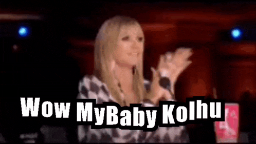 a woman is clapping her hands in front of a crowd .