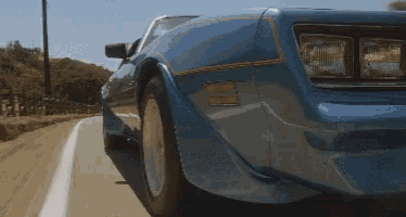 a blue car is driving down a road with a white line