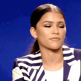 a woman wearing a striped jacket and earrings is making a funny face