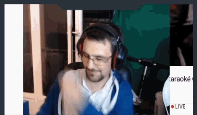 a man wearing headphones is sitting in front of a green screen that says live on it