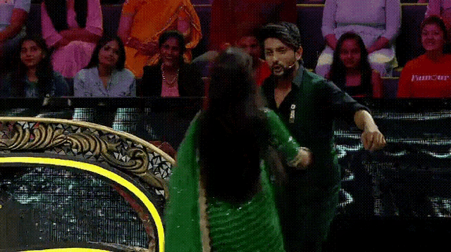 a woman in a green saree is being helped by a man