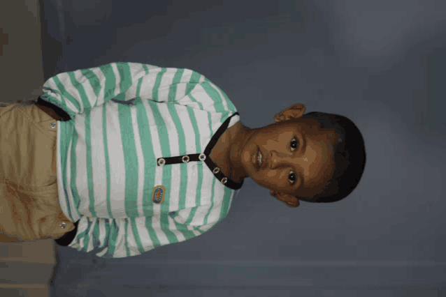 a young boy in a green and white striped shirt