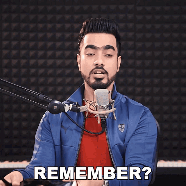a man singing into a microphone while holding a book with the word remember below him