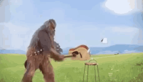 a chewbacca is swinging a hammer at a stool in a field .