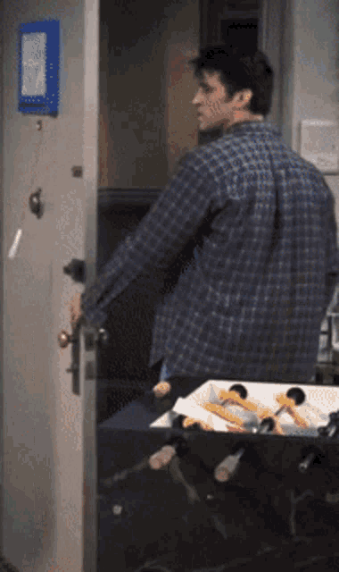 a man in a plaid shirt is standing in front of a door with a picture on it
