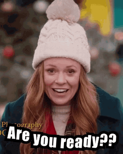 a woman wearing a white hat and scarf is smiling and says are you ready