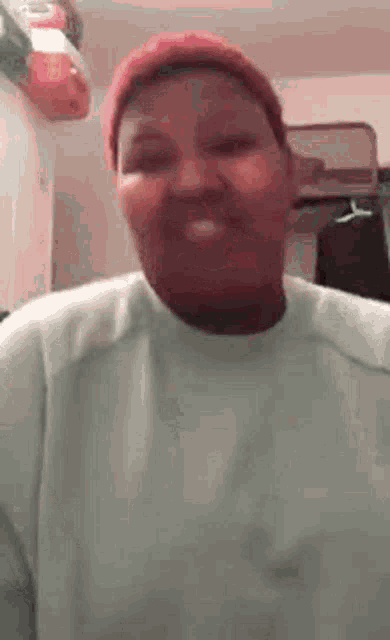 a woman wearing a red hat and a white sweater is smiling for the camera .