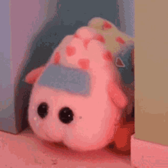 a pink stuffed animal is sitting in a corner of a room .