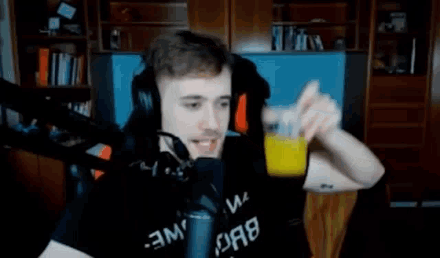 a man is holding a glass of orange juice in front of a microphone .