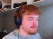 a man with red hair and a beard is wearing headphones and making a funny face .