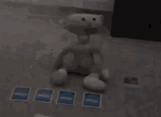 a stuffed animal is sitting on a table next to a pile of cards .