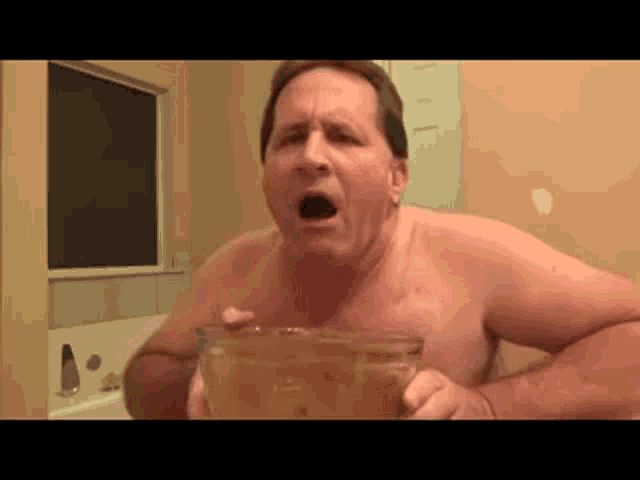 a shirtless man is sitting in a bathtub holding a bowl of food .