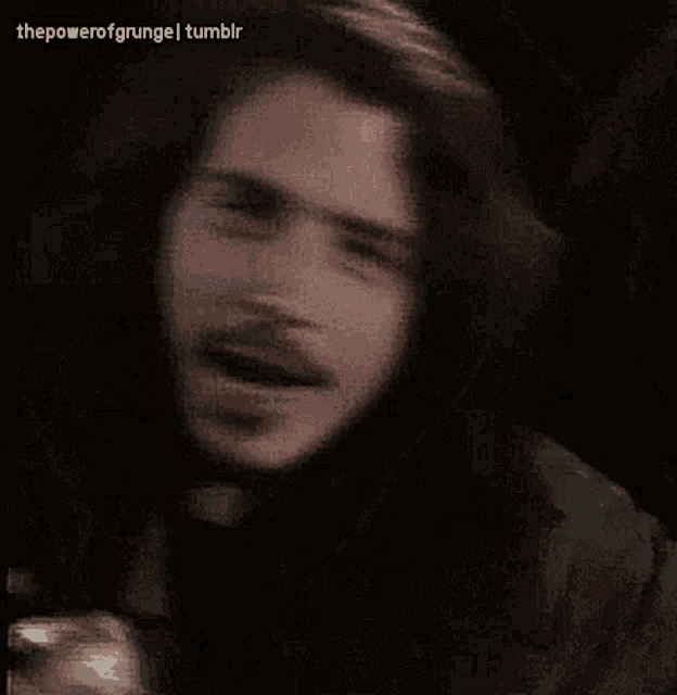 a man with long hair and a beard looks at the camera with the power of grunge tumblr written below him